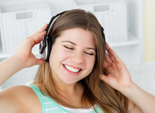 Fröhliche junge Frau hört Musik mit Kopfhörer auf einem sof — Stockfoto