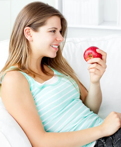 Gelukkig jonge vrouw met een appel op een sofa — Stockfoto