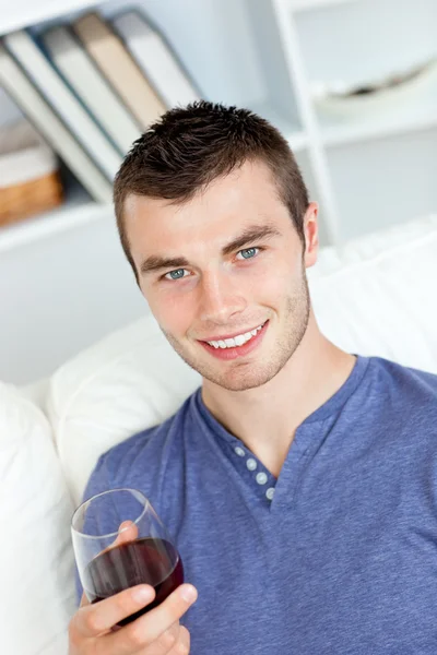 ソファーに座ってワインのガラスを保持しているカリスマ的な若い男 — ストック写真