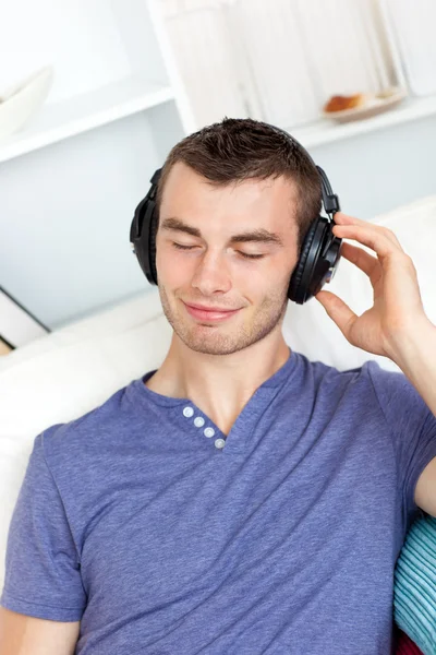 Handsome young man listening to music with headphones in the liv — Stock Photo, Image
