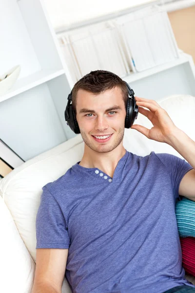 Entspannter junger Mann hört Musik mit Kopfhörern — Stockfoto