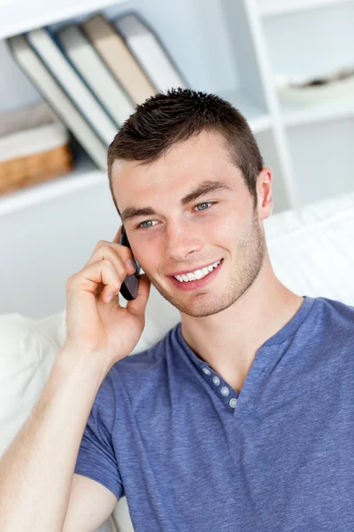 Šťastný mladý muž mluví telefonu sedí na pohovce — Stock fotografie