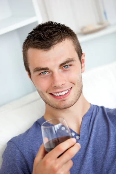 Animato giovane uomo bere vino guardando la fotocamera seduta o — Foto Stock