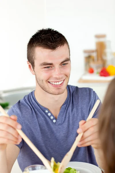 Homem feliz colocando salada em um prato jantando com sua namorada — Fotografia de Stock