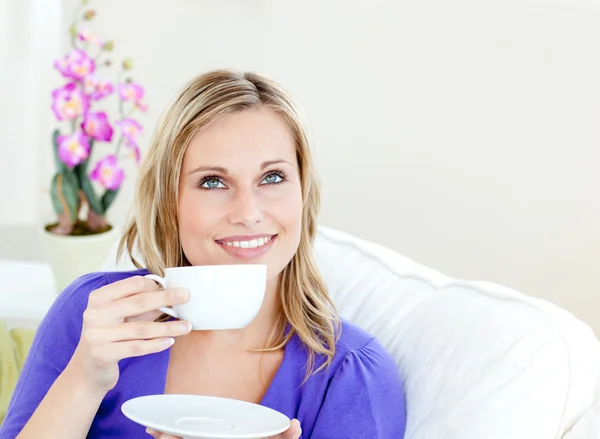 Mujer brillante disfrutando de su café sentado en un sofá en el salón —  Fotos de Stock