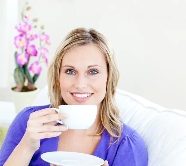 Charming woman enjoying her coffee sitting on a sofa in the livi — Stock Photo, Image