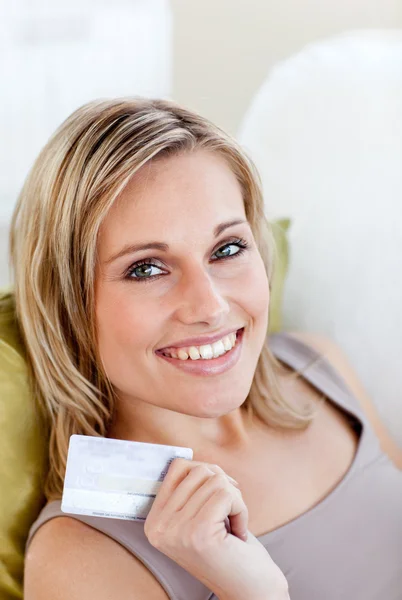 Mulher caucasiana alegre segurando um cartão sentado em um sofá no — Fotografia de Stock
