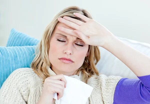 Mujer enferma con dolor de cabeza tumbada en el sofá del salón —  Fotos de Stock