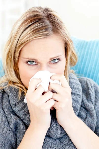Mujer enferma usando un pañuelo sentado en un sofá —  Fotos de Stock