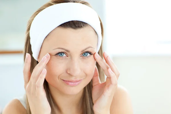 Heldere jonge vrouw crème op haar gezicht in de badkamer op te zetten — Stockfoto