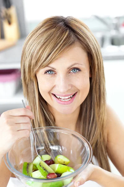 Mujer sonriente comiendo una ensalada de frutas sonriendo a la cámara en el —  Fotos de Stock