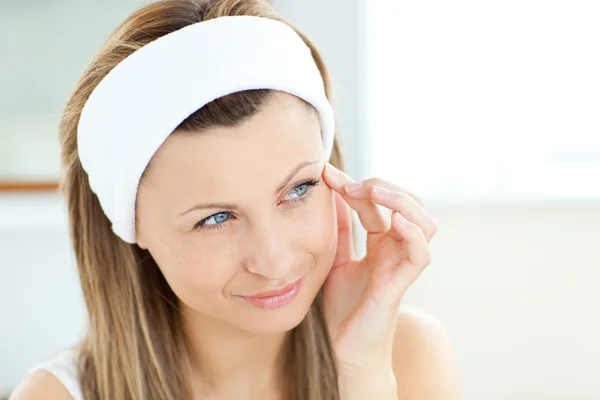 Mooie vrouw zetten crème op haar gezicht dragen een hoofdband in de — Stockfoto