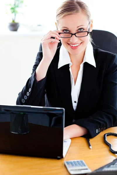 Carismática mujer de negocios sosteniendo sus gafas y usando su lapt —  Fotos de Stock