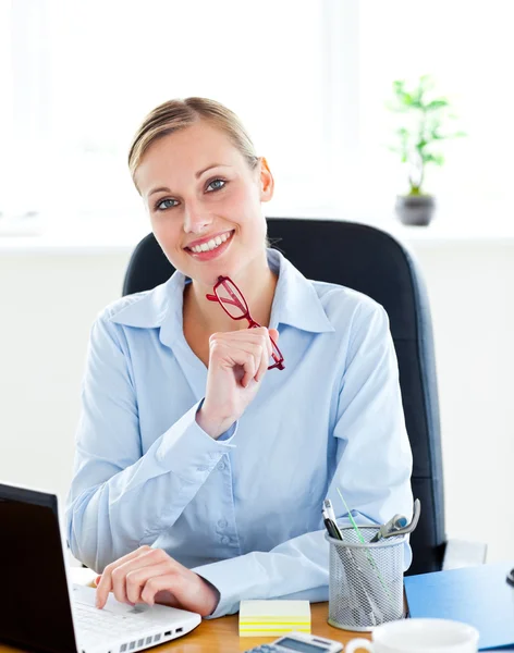 Confident businesswoman holding her glasses in her office — Stock Photo, Image