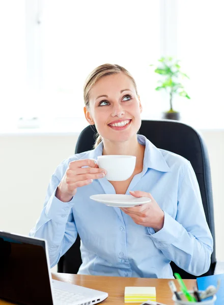 Empresária encantada bebendo café na frente de seu laptop i — Fotografia de Stock