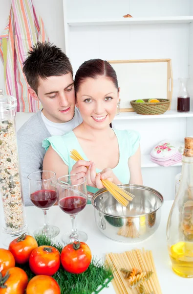 Giovane coppia che prepara spaghetti in cucina e beve vino — Foto Stock