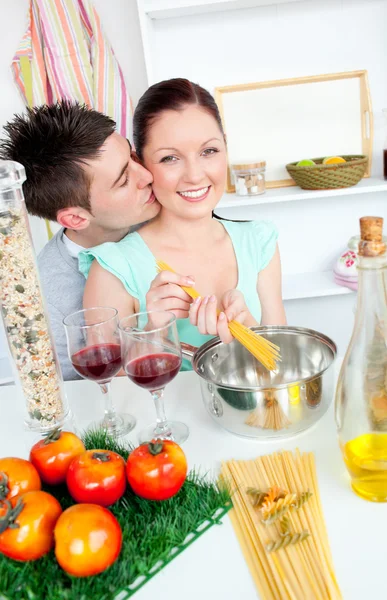 Bright couple preparing spaghetti in the kitchen and drinking win — стоковое фото