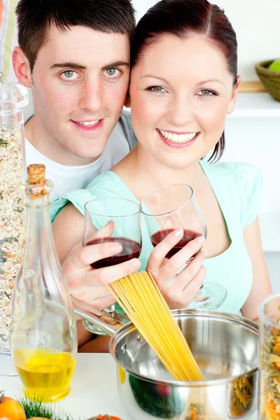 Pareja feliz preparando espaguetis en la cocina y beber vino — Foto de Stock