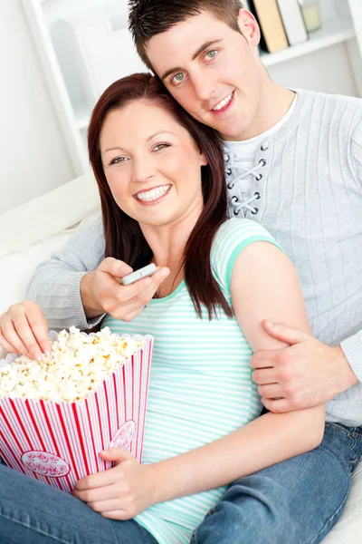 Pärchen umarmt, Popcorn isst und auf dem Bett liegend fernsieht — Stockfoto