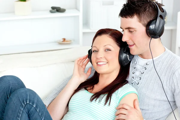 Charmantes Paar hört Musik mit Kopfhörern auf dem Bett liegend — Stockfoto