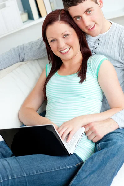恩爱的夫妻在沙发上使用一台笔记本电脑 — 图库照片