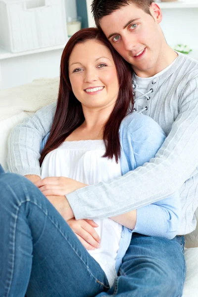 Porträt eines sich umarmenden Paares, das auf einem Sofa im Wohnzimmer sitzt — Stockfoto