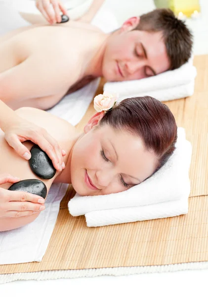 Encantador jovem casal recebendo uma massagem nas costas com pedras quentes — Fotografia de Stock