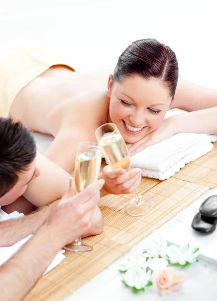 Amante jovem casal bebendo champanhe deitado em uma mesa de massagem — Fotografia de Stock