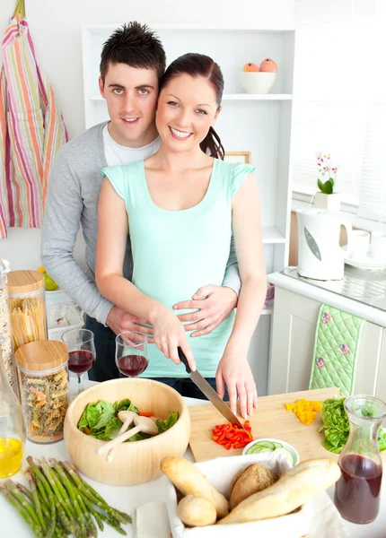 Enamorado jovem casal cortando legumes na cozinha — Fotografia de Stock