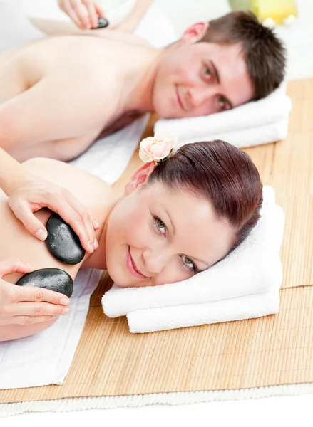 Atractiva pareja joven recibiendo un masaje de espalda con piedras calientes — Foto de Stock