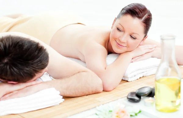 Adorável jovem casal deitado em uma mesa de massagem — Fotografia de Stock