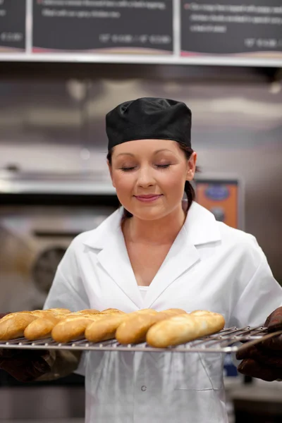 Cute young baker smelling baguettes — Stock Photo, Image