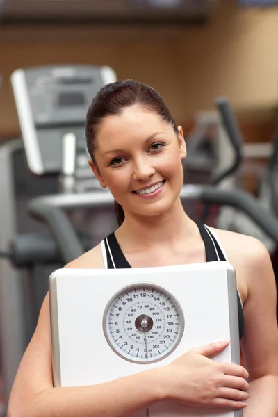 Cute woman holding a scales and smiling at the camera — Stock Photo, Image