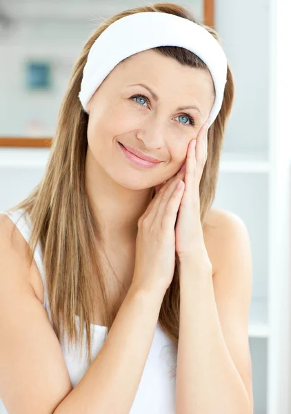 Jonge vrouw zetten crème op haar gezicht dragen een hoofdband in de — Stockfoto