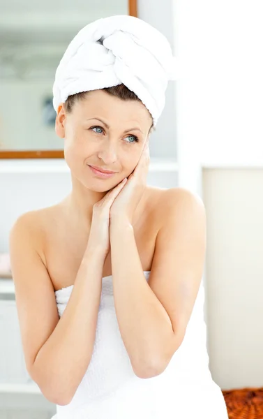 Affascinante giovane donna con un asciugamano mettendo crema sul viso in t — Foto Stock