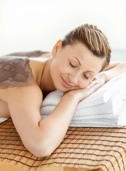 Merry caucasian woman lying on a massage table with mud on her b — Stock Photo, Image