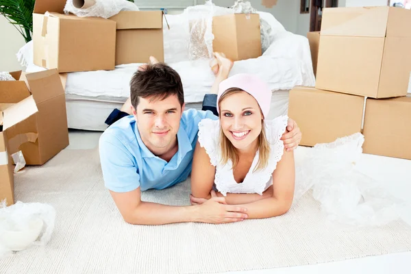 Jolly couple lying on the floor between boxes — Stock Photo, Image