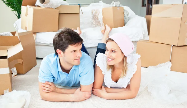 Young couple lying on the floor after unpacking boxes — Stock Photo, Image