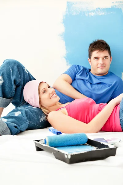 Brilhante jovem casal relaxante depois de pintar um quarto — Fotografia de Stock