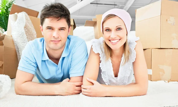 Smiling couple lying on the floor after unpacking boxes — Stock Photo, Image