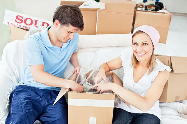Joyful caucasian couple unpacking boxes with glasses — Stock Photo, Image
