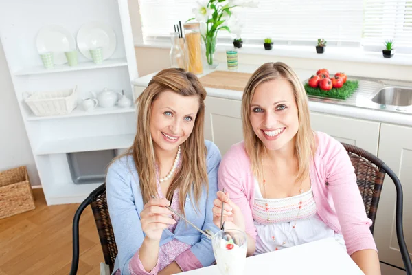 Delighted friends eating an ice cream and smiling at the camera — Stock Photo, Image