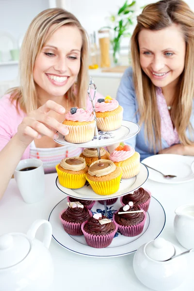 Giovani donne positive che mangiano torte in cucina — Foto Stock