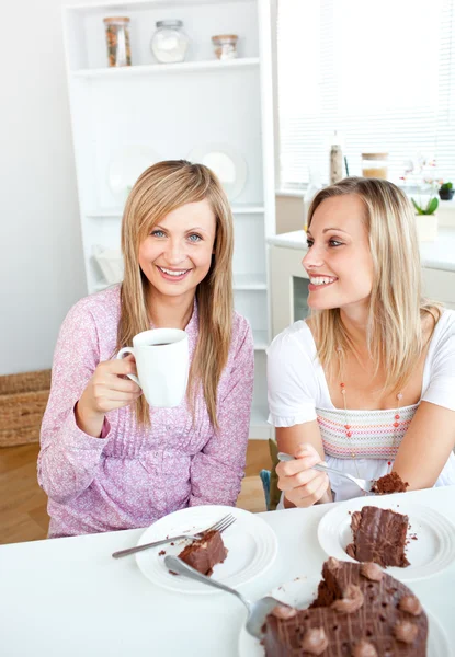 Happy female friends eating a chocolate cake and drinking in the — Stock Photo, Image