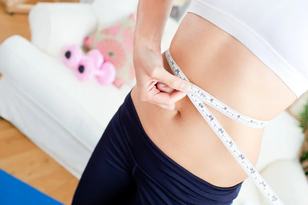 Close-up of a caucasian woman measuring her waist with a tape in — Stock Photo, Image