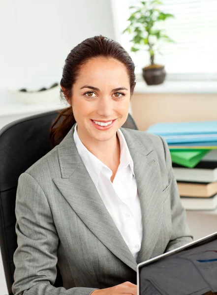 Charismatische jonge zakenvrouw met behulp van haar laptop zit op haar — Stockfoto
