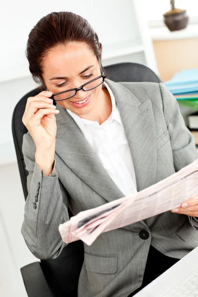 Giovane donna d'affari deliziata che tiene gli occhiali leggendo un giornale — Foto Stock