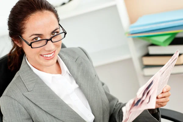 Joyful businesswoman wearing glasses and holding a newspaper in — Stock Photo, Image