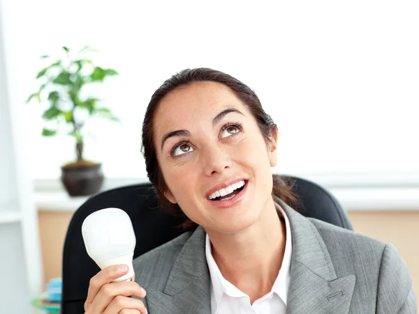 Sorpresa donna d'affari in possesso di una lampadina seduta nel suo offi — Foto Stock