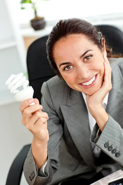 Vacker affärskvinna håller en glödlampa i hennes hand sitter — Stockfoto